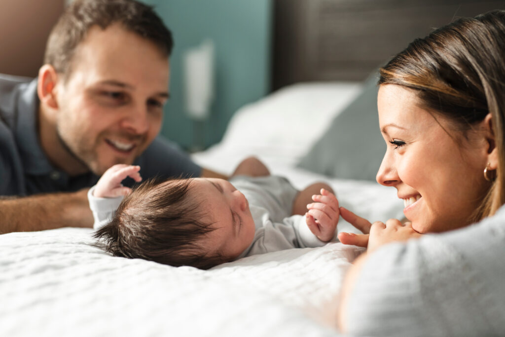 A beautiful couple with a newborn baby on bed.