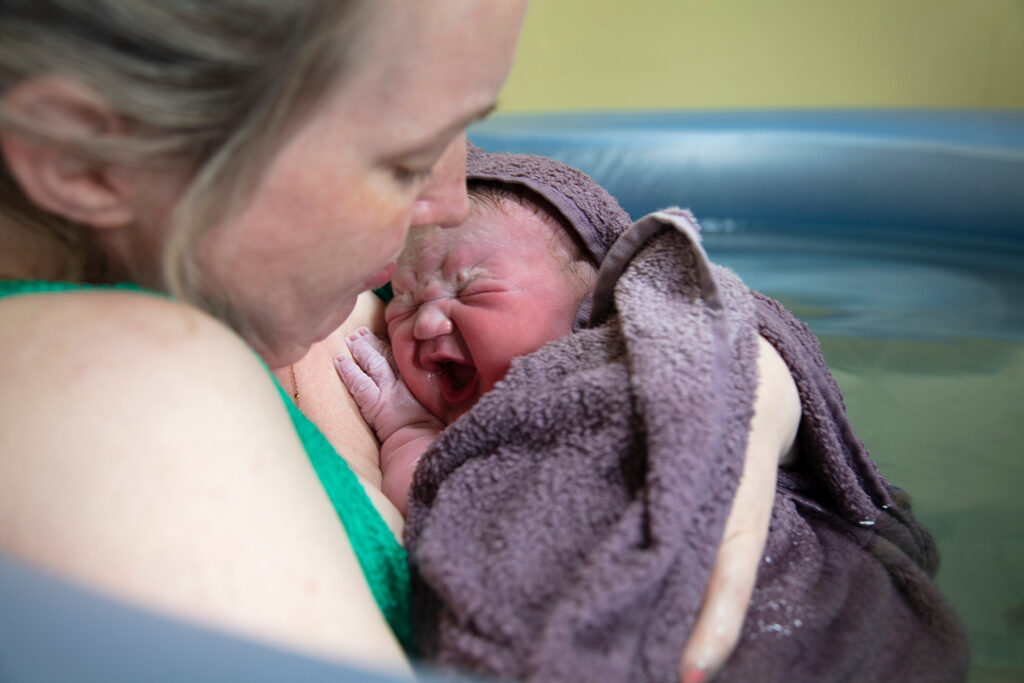 A new mother embracing her newborn baby after a pool birth