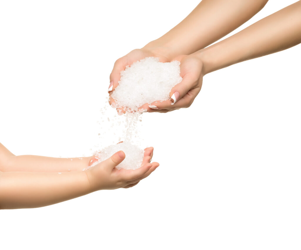 Sea salt crystals in women hand and child hand.