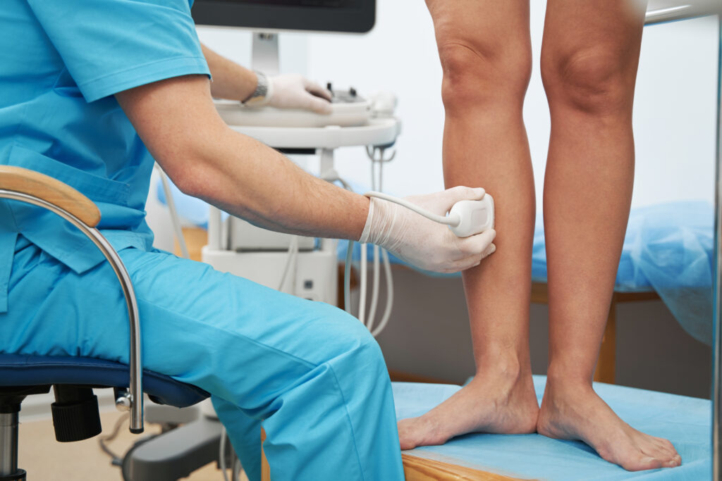 Medical worker sitting in chair carefully examining the patient veins using an ultrasound machine